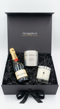 luxury champagne gift bx with jo malone andle and champagne truffles from hotel chocolat, black shredded paper on a white professional background.